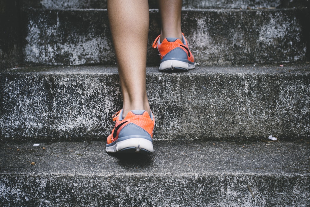 close up of someone wearing training shoes going up concrete steps