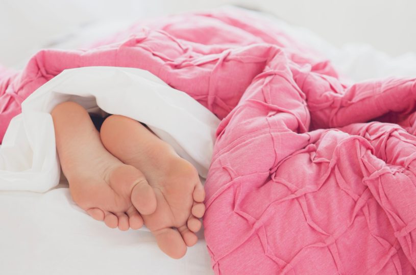 image of bare feet under blankets in bed