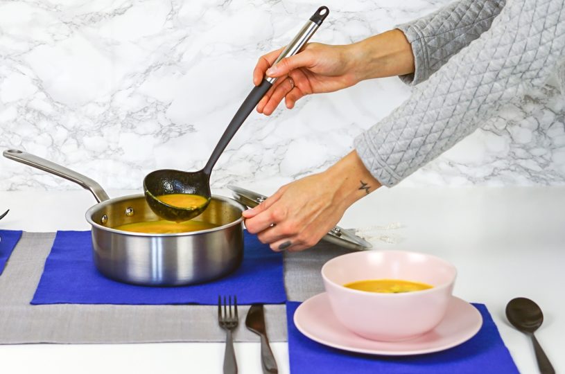 woman ladling soup from a pot