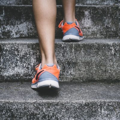 close up of someone wearing training shoes going up concrete steps